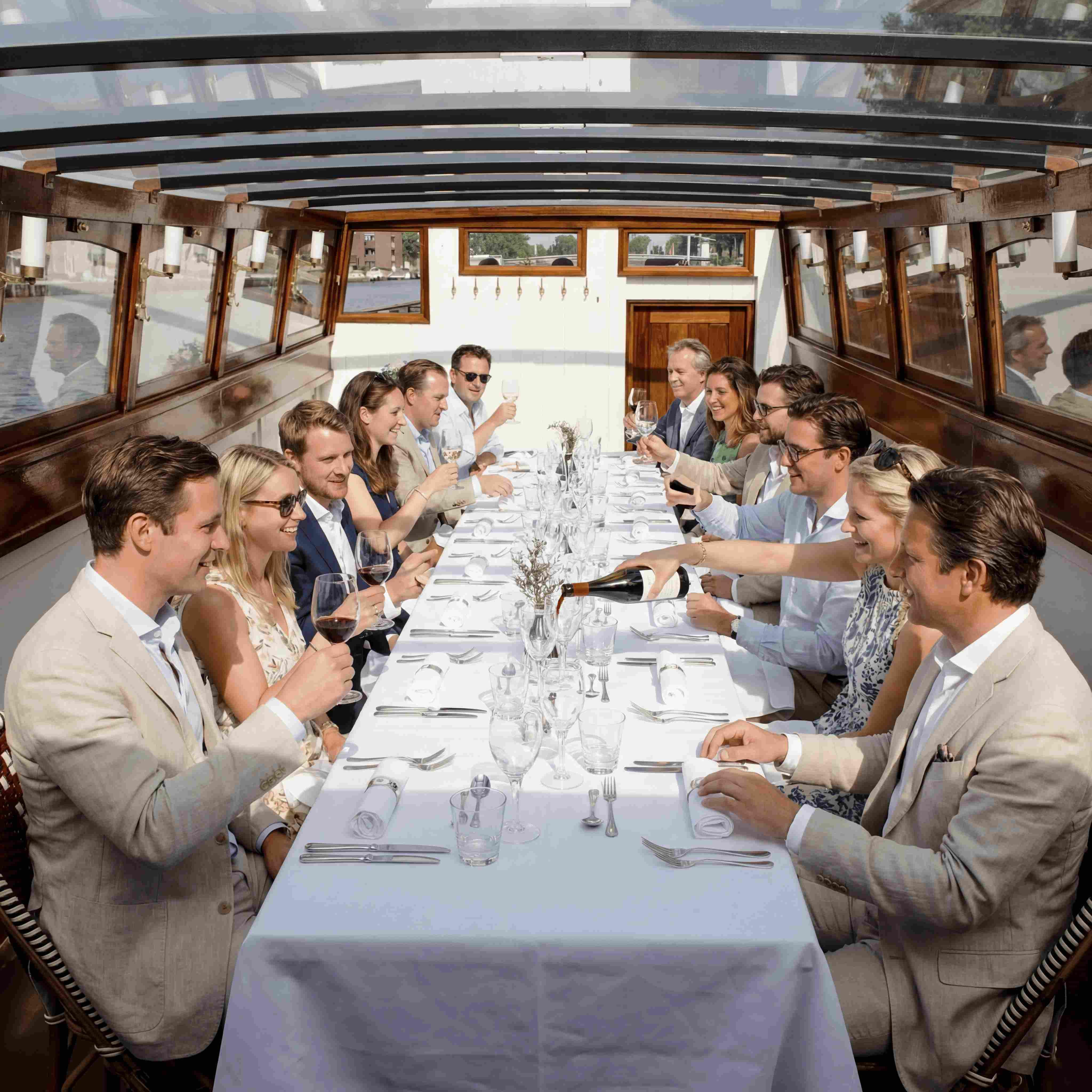 Gasten dineren aan een feestelijk gedekte tafel in een salonboot