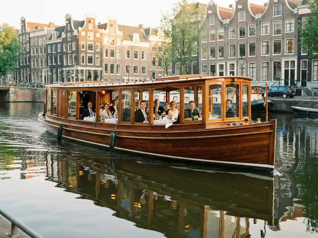 Klassieke overdekte Nederlandse salonboot uit 1910 vaart door Amsterdamse grachten met historische grachtenpanden